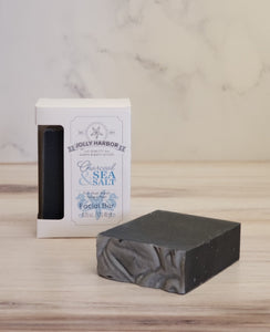 charcoal black bar soap on pale wood table.